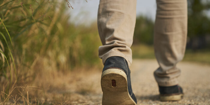 Close up of the feet of a man walking on a gravel trail