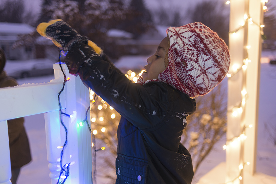 Boy hanging Christmas lights in the the winter